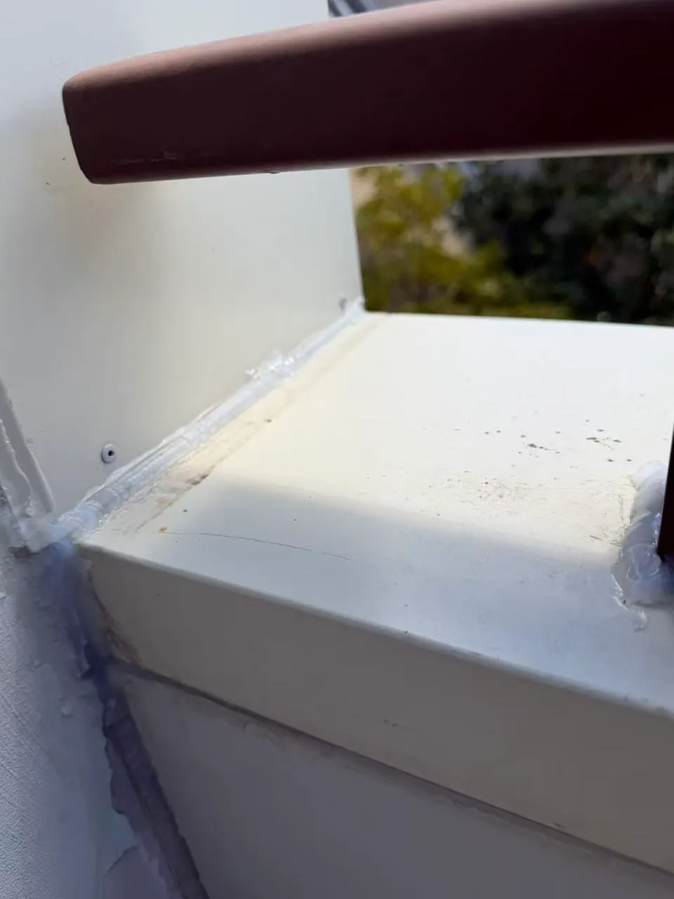 Sealant is visible where the balcony capping meets the wall beside the railing.