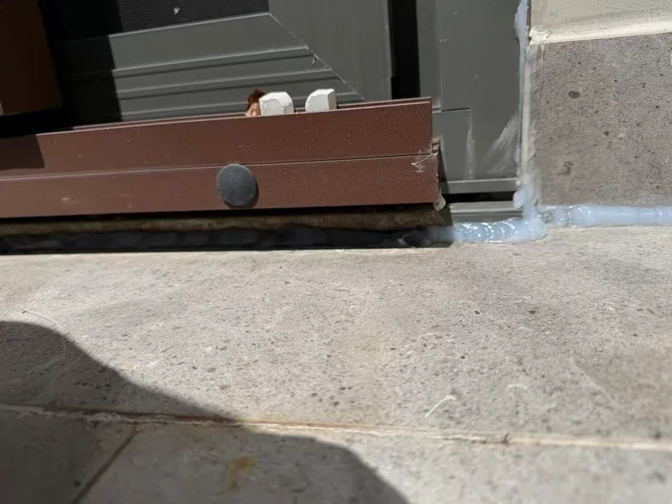 The sliding-door threshold meets the tiled upstand and balcony floor.