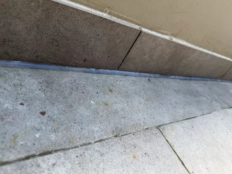 The floor-edge sealant line continues beside the tiled upstand.